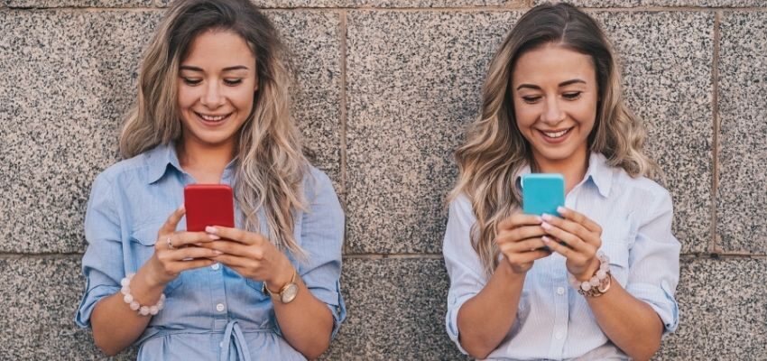 Two women smiling while browsing on social media.