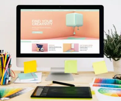 Creative workspace with colorful stationery and website matching colors on a desktop screen