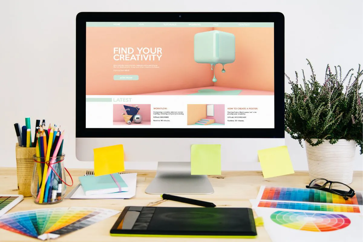 Creative workspace with colorful stationery and website matching colors on a desktop screen