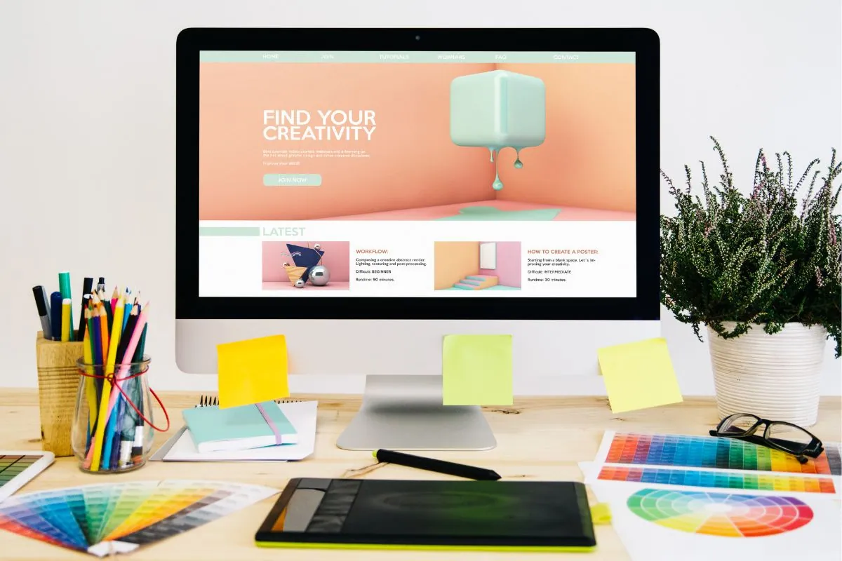 Creative workspace with colorful stationery and website matching colors on a desktop screen