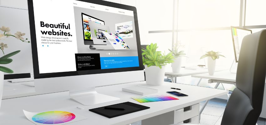 Sleek office setup with website matching colors on screen, surrounded by plants and design tools.