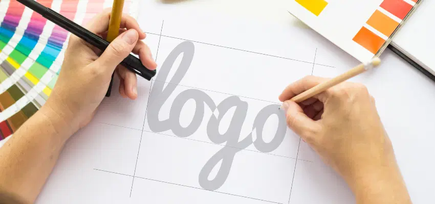 Someone drawing the word "logo" on a piece of white paper.