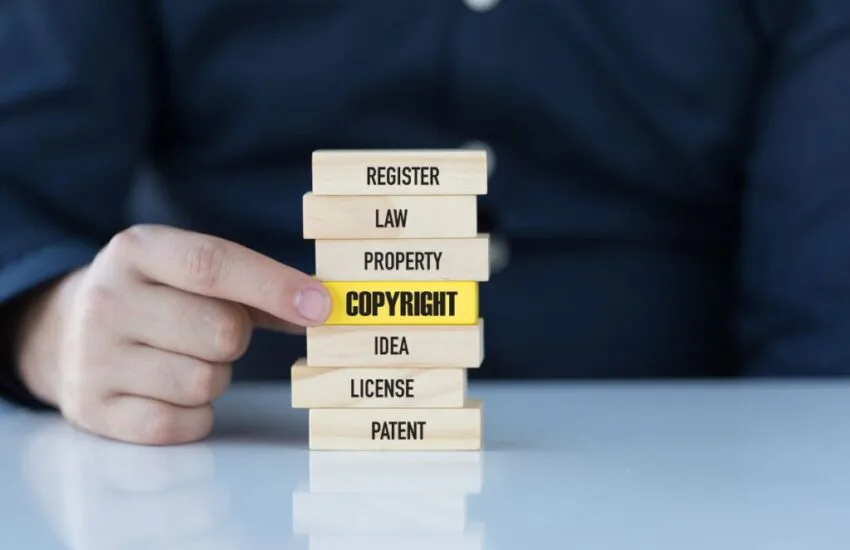 image is copyrighted (1) The man holds a wooden block with a keyword relevant to a copyrighted image.
