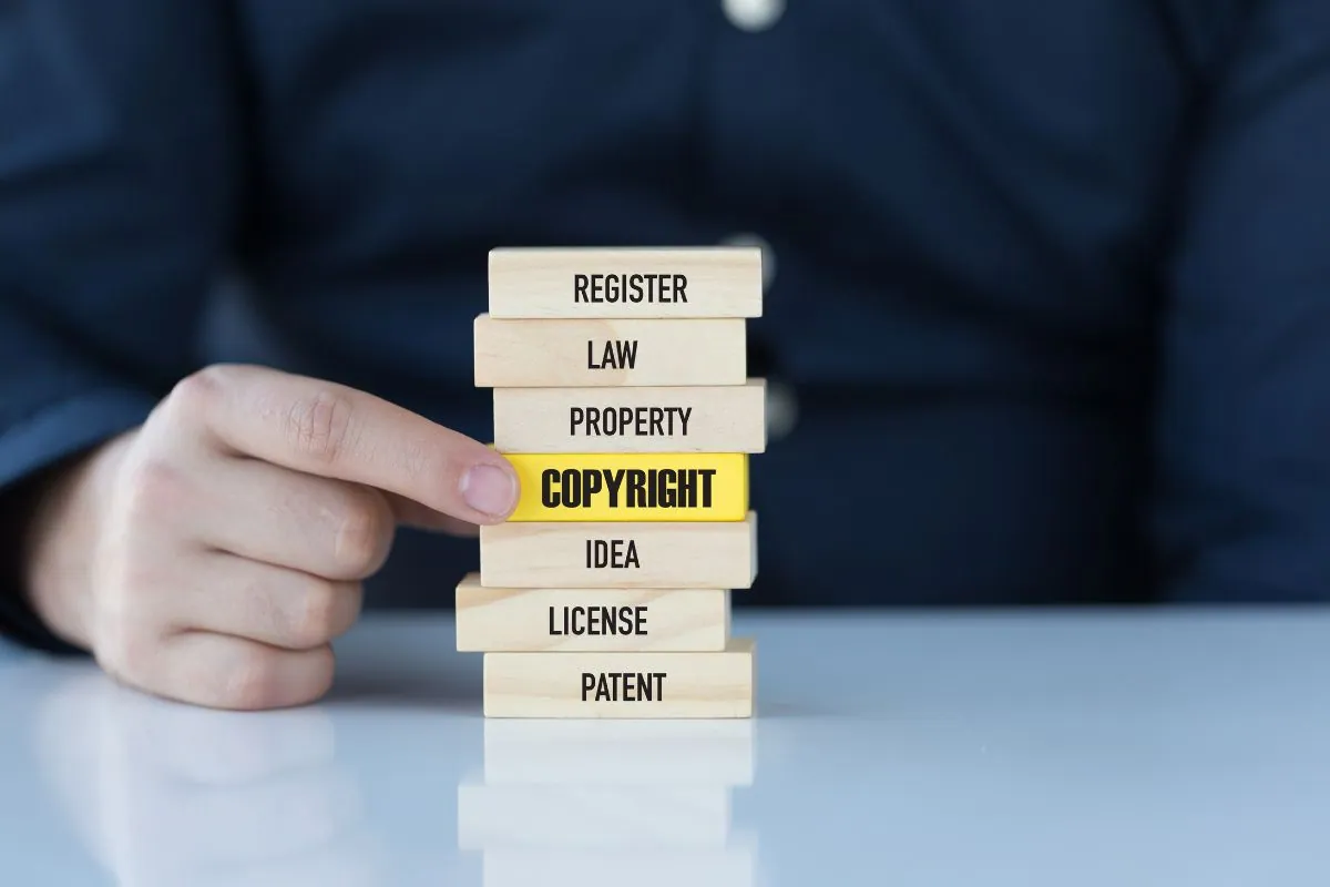 The man holds a wooden block with a keyword relevant to a copyrighted image.