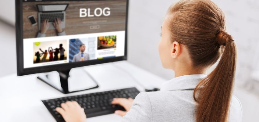blogs-with-jasper-ai2 A woman with a ponytail sits at a desk viewing a blog website on a desktop screen, representing professional content creation for blogs with Jasper AI.