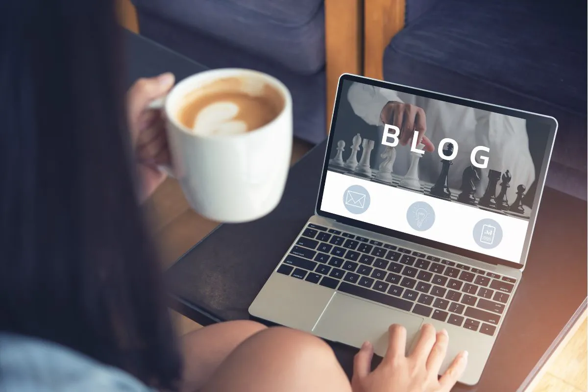 A person holding a cup of coffee while using a laptop, capturing the relaxed atmosphere of writing blogs with Jasper AI.
