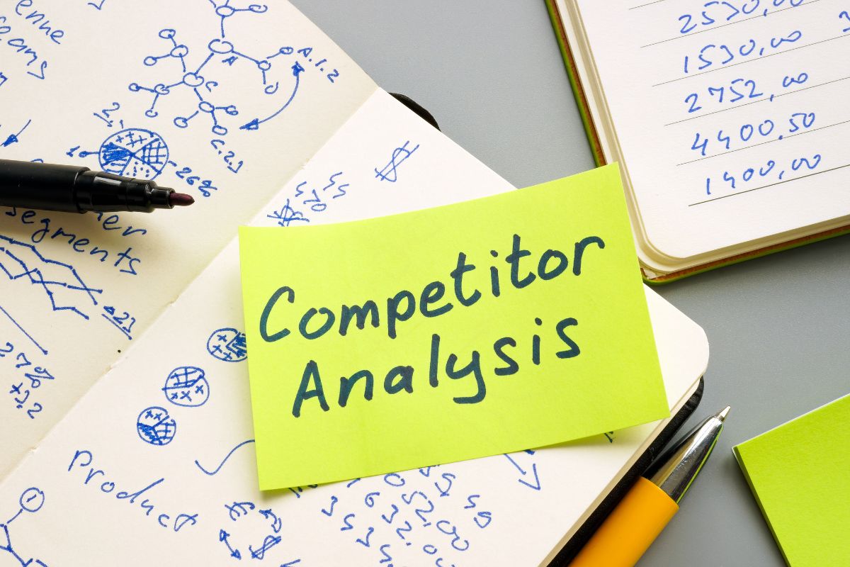 A table of planners and a sticky note with the words "competitor analysis" which means monitor competitors