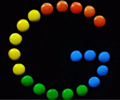 Colorful candy pieces arranged to form a stylized “G” on a black background, creatively representing the playful branding and team culture in the Google organizational structure.
