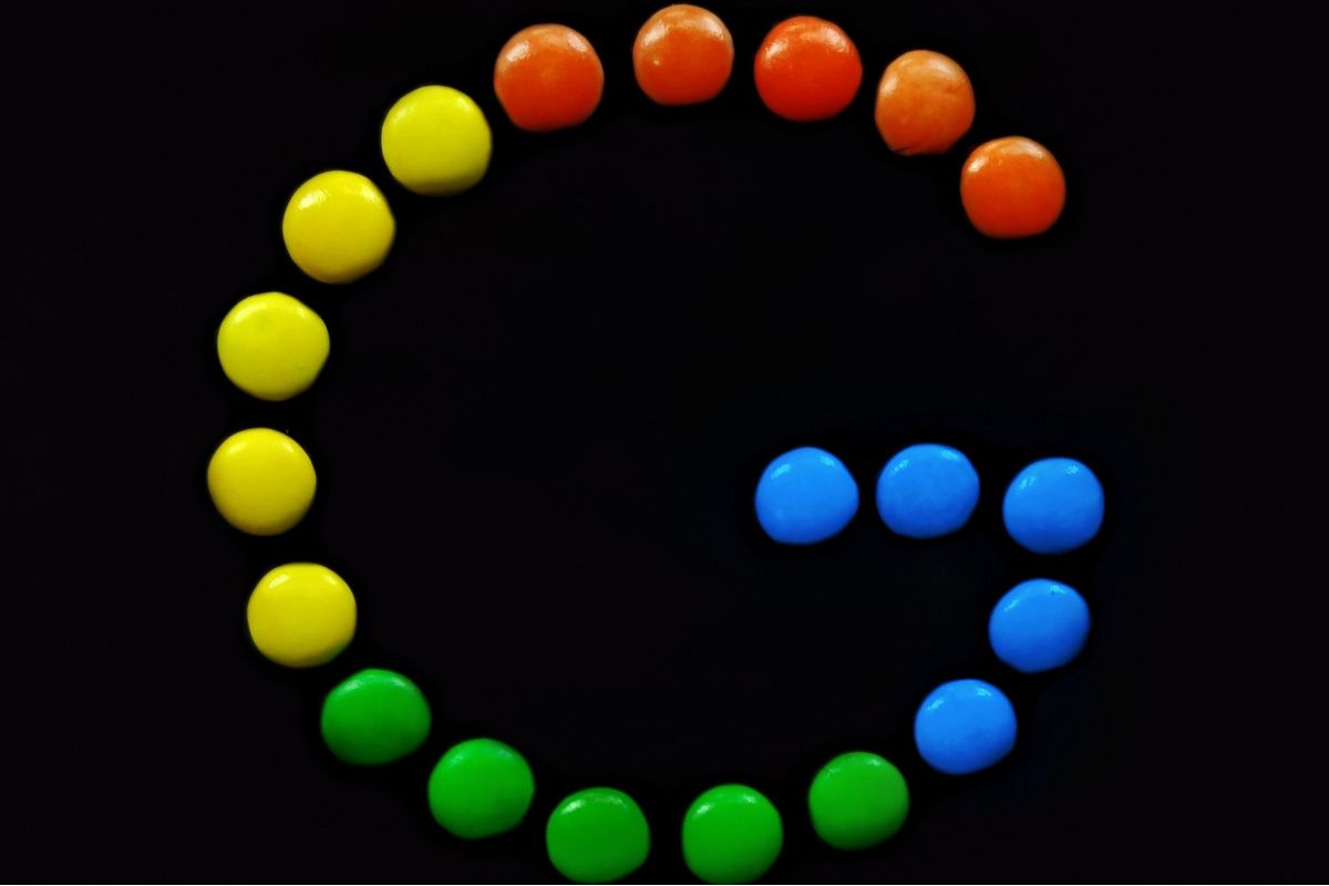 Colorful candy pieces arranged to form a stylized “G” on a black background, creatively representing the playful branding and team culture in the Google organizational structure.