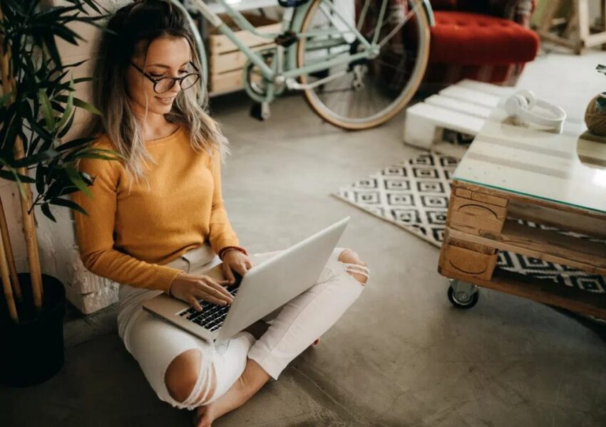 A woman sitting with her laptop on her lap.