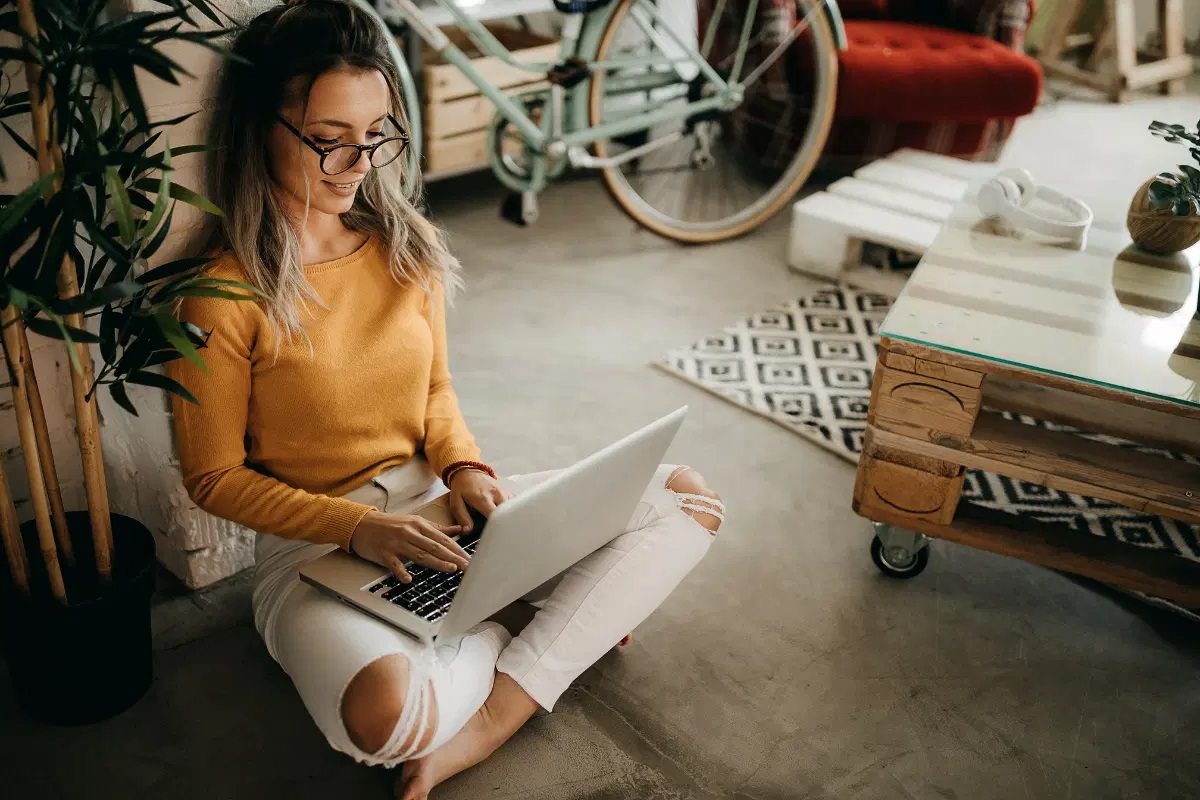 A woman sitting with her laptop on her lap.